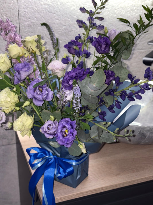 Šaltų tonų gėlių puokštė su mėlynais, violetiniais ir šviesiais atspalviais, vertikali, lengva ir subalansuota kompozicija